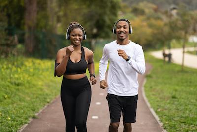 Black man and woman smiling and running in a park, wilmington de