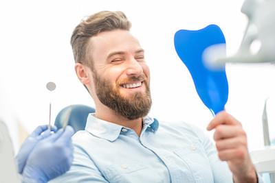 White man smiling in dental chair while looking at mirror, wilmington de