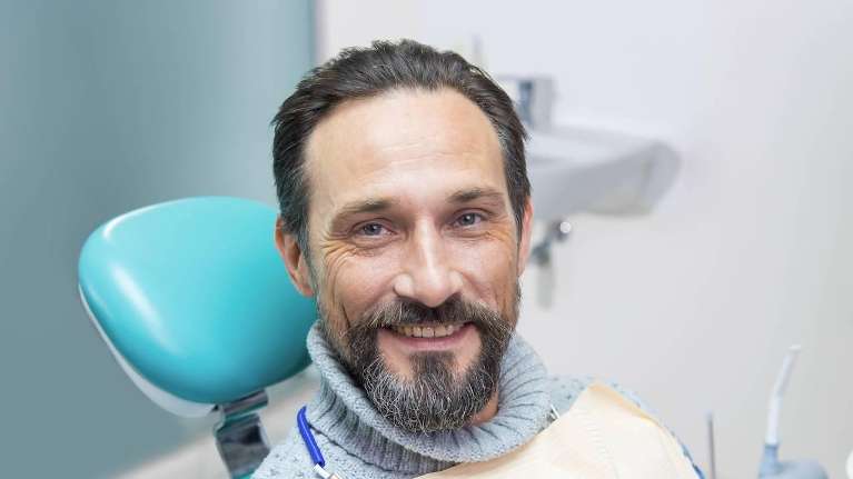 Middle aged man smiling in dentist chair, wilmington de